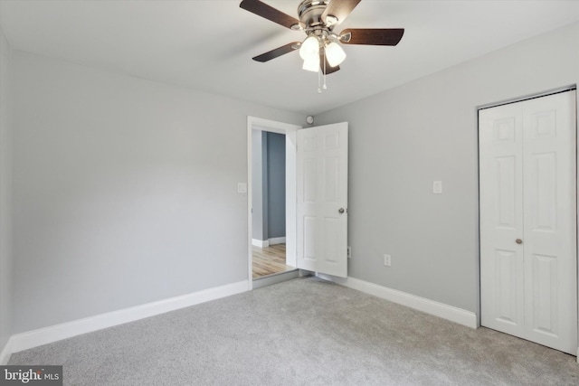 unfurnished bedroom with ceiling fan, light colored carpet, and a closet