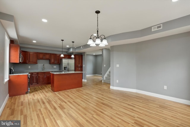 kitchen with light wood-type flooring, a center island, a notable chandelier, stainless steel refrigerator with ice dispenser, and decorative light fixtures