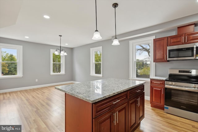 kitchen featuring light hardwood / wood-style flooring, stainless steel appliances, hanging light fixtures, and light stone countertops