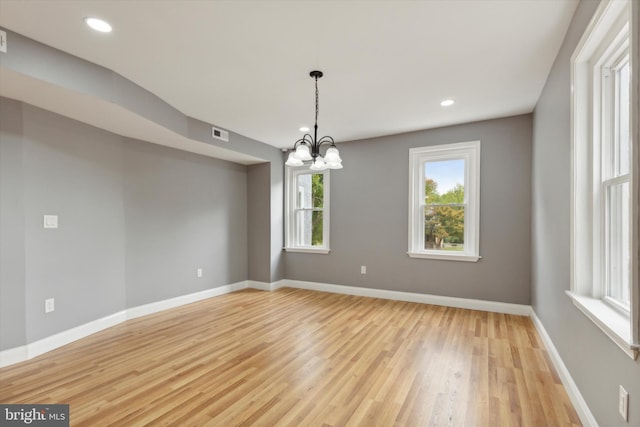 empty room with light wood-type flooring and a chandelier