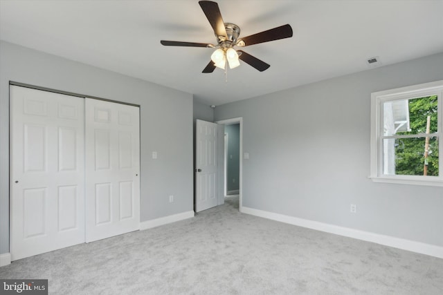 unfurnished bedroom featuring ceiling fan, light colored carpet, and a closet