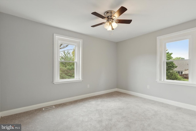 carpeted spare room with ceiling fan and a healthy amount of sunlight