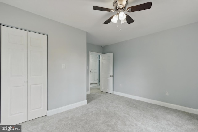 unfurnished bedroom featuring ceiling fan, a closet, and light carpet