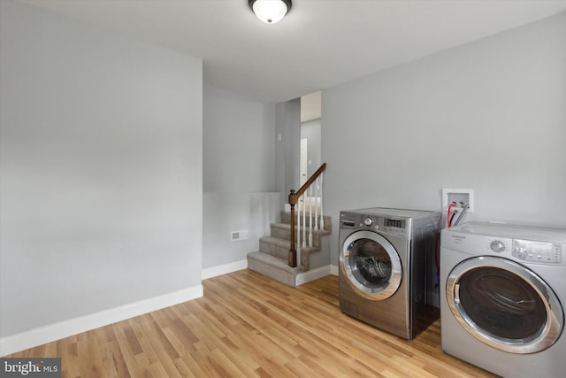 clothes washing area with light hardwood / wood-style floors and washing machine and dryer