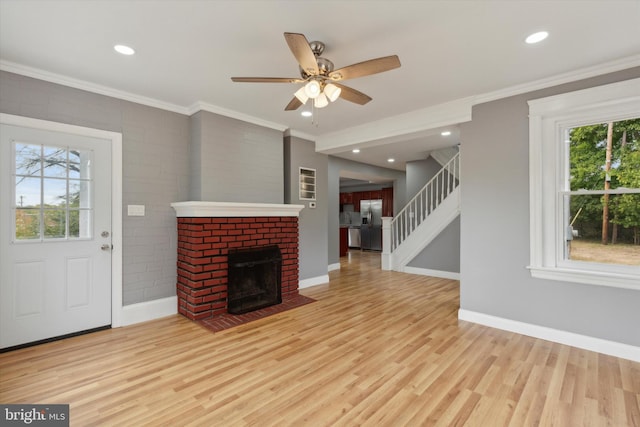 unfurnished living room featuring light hardwood / wood-style floors, a fireplace, ceiling fan, and a wealth of natural light