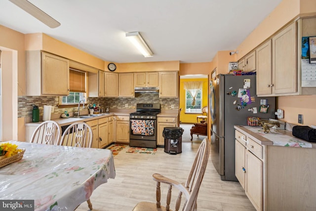 kitchen with light wood-type flooring, light brown cabinets, black range with gas stovetop, and sink