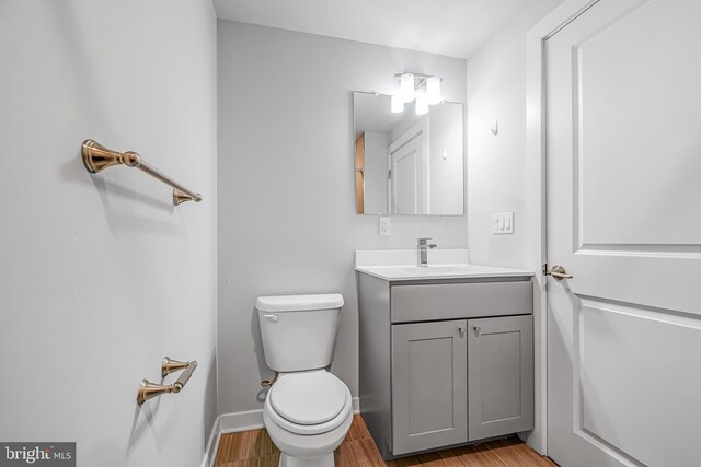 bathroom featuring toilet, vanity, and hardwood / wood-style floors