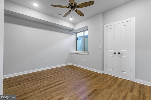 unfurnished bedroom featuring hardwood / wood-style floors, a closet, and ceiling fan