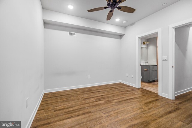 unfurnished bedroom featuring ensuite bathroom, dark wood-type flooring, ceiling fan, and sink