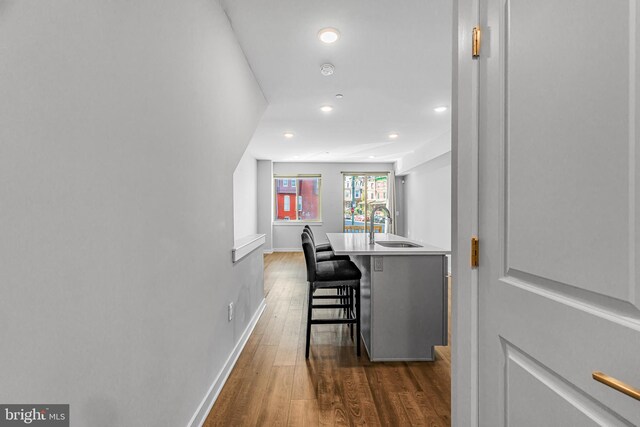 interior space featuring sink, a center island with sink, a kitchen breakfast bar, and dark hardwood / wood-style floors