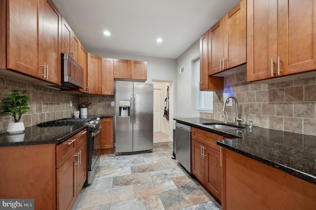 kitchen featuring stainless steel appliances, sink, dark stone counters, and tasteful backsplash