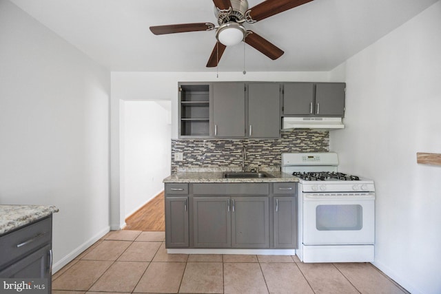 kitchen featuring ceiling fan, sink, gray cabinetry, white range with gas cooktop, and decorative backsplash