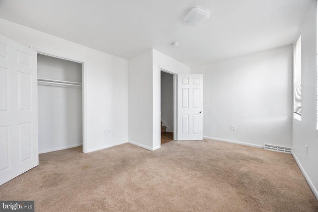 unfurnished bedroom featuring light carpet and a closet