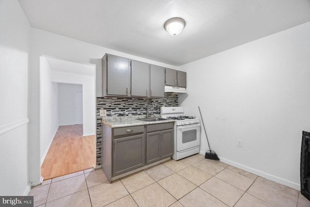 kitchen featuring white gas range, sink, gray cabinets, and tasteful backsplash