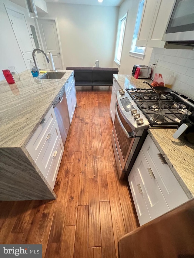 kitchen featuring light stone countertops, white cabinetry, sink, and stainless steel appliances