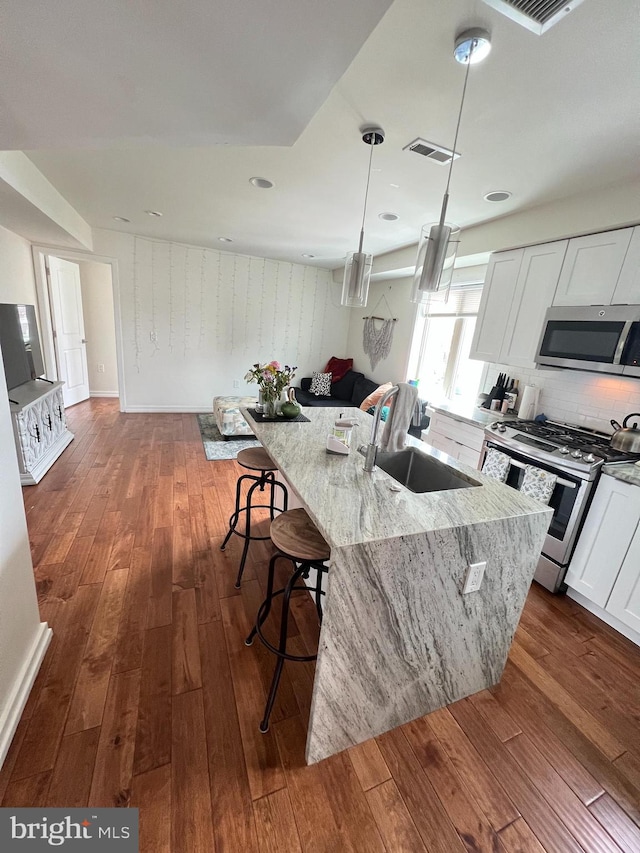 kitchen featuring an island with sink, appliances with stainless steel finishes, sink, and white cabinetry