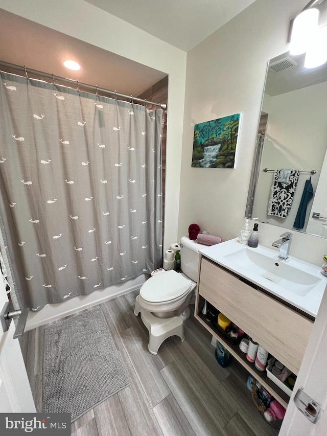 full bathroom with shower / bath combination with curtain, hardwood / wood-style flooring, vanity, and toilet