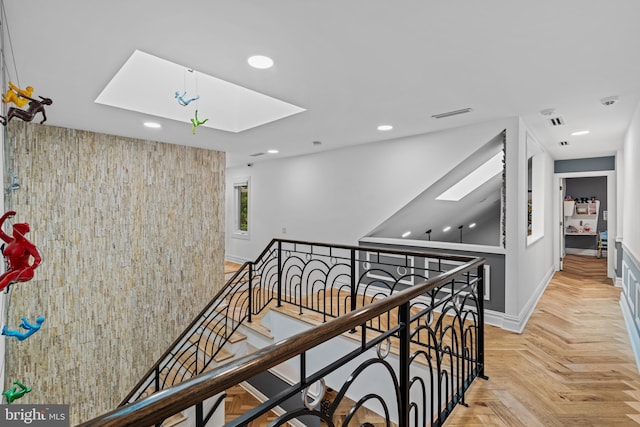 hallway with light parquet floors and a skylight