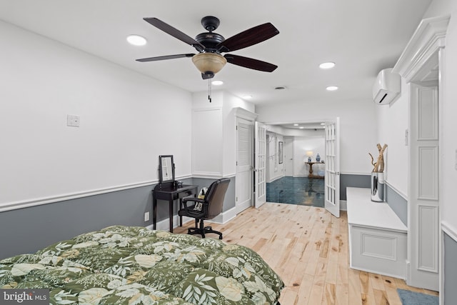 bedroom featuring french doors, an AC wall unit, light wood-type flooring, and ceiling fan