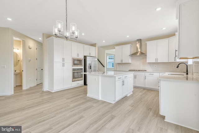 118 Pawn Ct, Winchester, VA 22602 - kitchen featuring stainless steel appliances, wall chimney range hood, a sink, light wood-style floors, and tasteful backsplash