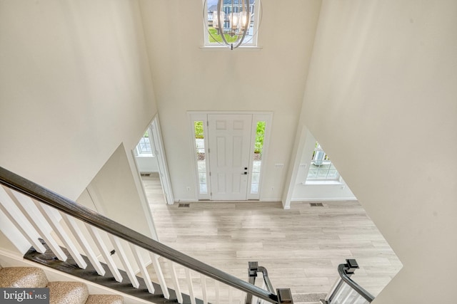 foyer entrance with visible vents, a high ceiling, wood finished floors, and stairs