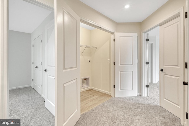 hallway featuring baseboards and light colored carpet