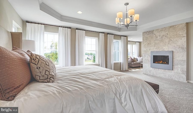 carpeted bedroom with crown molding, a notable chandelier, a tray ceiling, and a fireplace