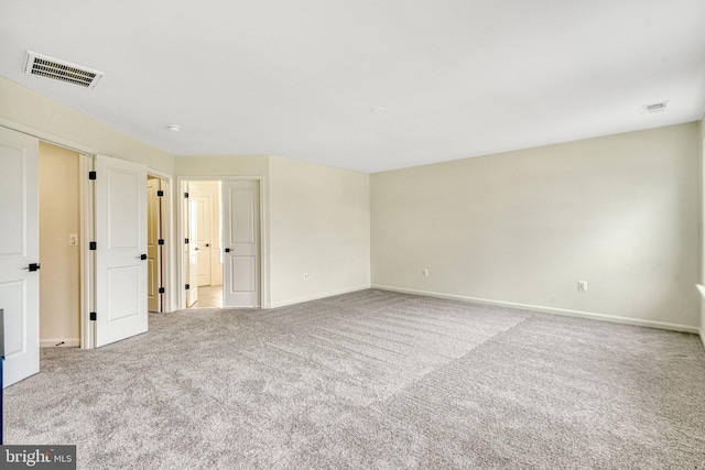 carpeted empty room featuring baseboards and visible vents