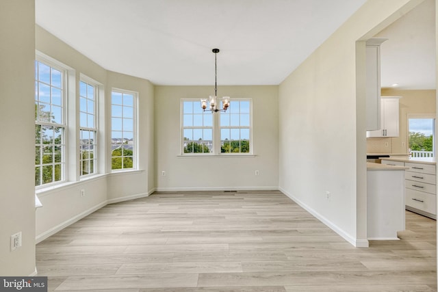 unfurnished dining area with a chandelier and light hardwood / wood-style flooring