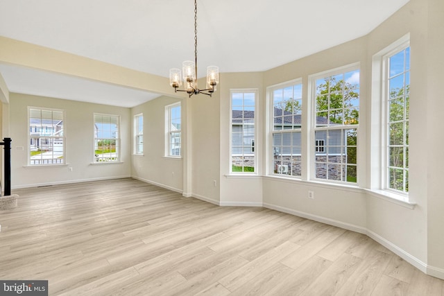 unfurnished dining area featuring a notable chandelier, baseboards, and light wood-style floors