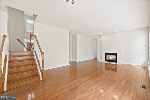 unfurnished living room with a multi sided fireplace and light hardwood / wood-style floors