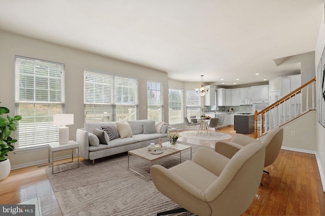 living room featuring light wood-type flooring, a chandelier, and plenty of natural light