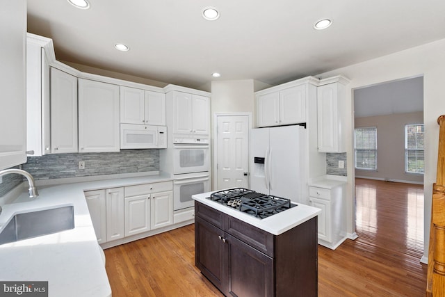 kitchen featuring light wood-type flooring, sink, white appliances, and white cabinetry