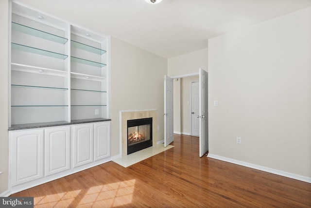 unfurnished living room featuring wood-type flooring and a multi sided fireplace