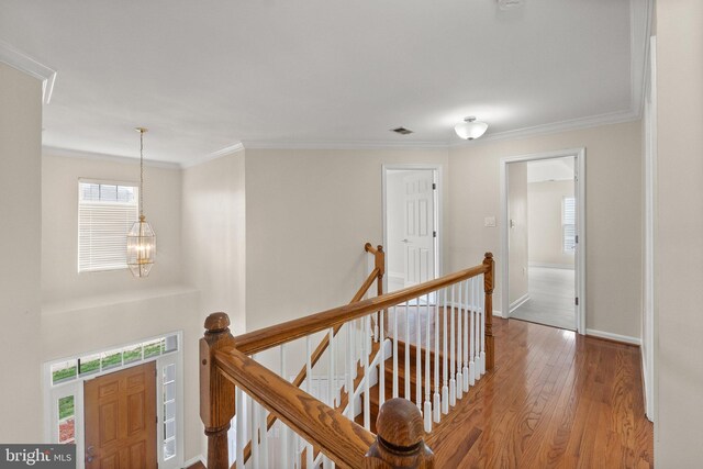 hall featuring ornamental molding, light hardwood / wood-style flooring, and a chandelier