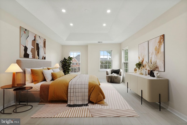 bedroom with a tray ceiling and light hardwood / wood-style flooring