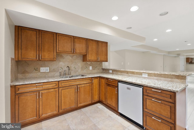 kitchen with light stone countertops, stainless steel dishwasher, sink, and kitchen peninsula