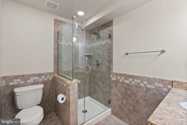 bathroom featuring tile walls, a shower with shower door, vanity, tile patterned flooring, and toilet