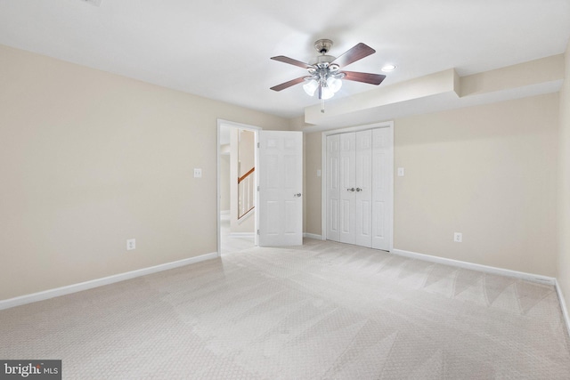 unfurnished bedroom with ceiling fan, light colored carpet, and a closet