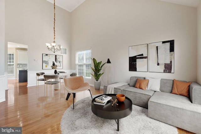 living room with high vaulted ceiling, a notable chandelier, hardwood / wood-style flooring, and crown molding