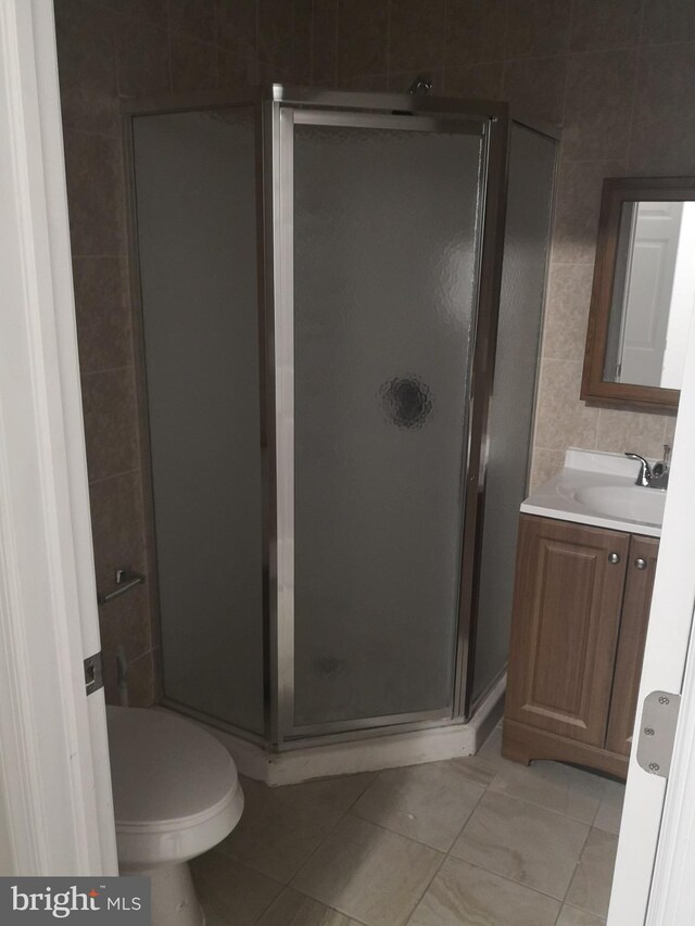 bathroom with walk in shower, vanity, toilet, and tile patterned floors