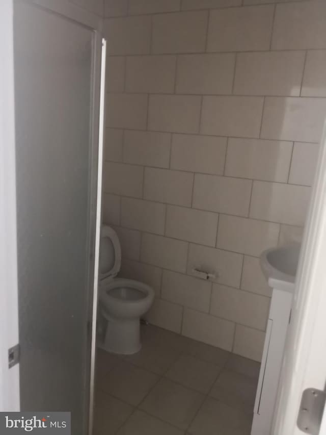 bathroom featuring walk in shower, vanity, tile patterned flooring, and toilet