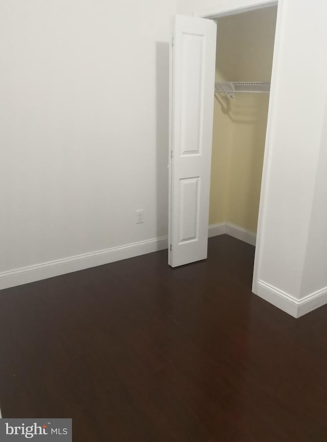 unfurnished bedroom with a closet and dark hardwood / wood-style flooring