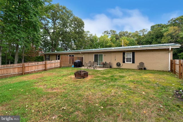 back of house featuring a yard, a patio, and an outdoor fire pit