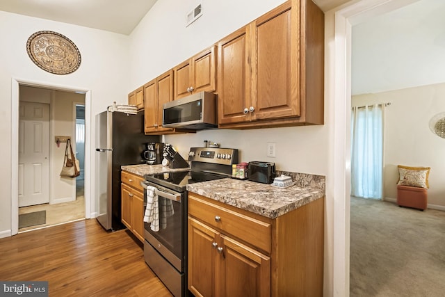 kitchen featuring light stone countertops, appliances with stainless steel finishes, and dark hardwood / wood-style flooring