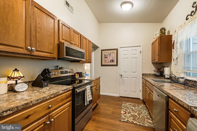 kitchen with stone counters, dark hardwood / wood-style flooring, sink, and stainless steel appliances