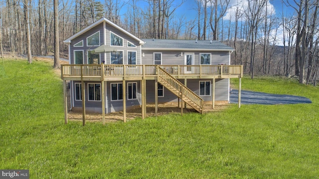 back of house featuring stairs, a deck, a view of trees, and a yard