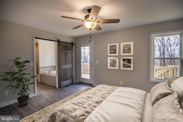 bedroom featuring multiple windows, a barn door, dark hardwood / wood-style floors, and access to outside