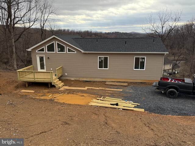 exterior space featuring a wooden deck and roof with shingles
