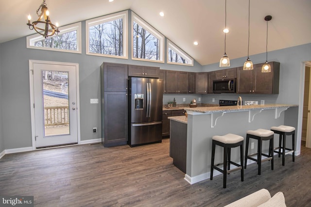 kitchen featuring pendant lighting, light stone countertops, dark brown cabinets, and stainless steel appliances